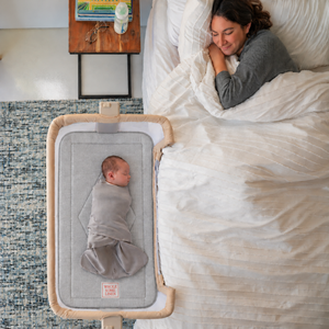 Wholesome Linen organic flax mattress for Baby Delight Beside Me Wink bassinet, gray linen mattress with embroidered logo and sleeping baby.
