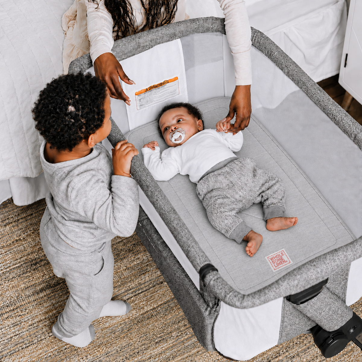 Wholesome Linen organic flax mattress for Baby Delight Beside Me Dreamer bassinet, gray linen mattress with embroidered logo and sleeping baby.